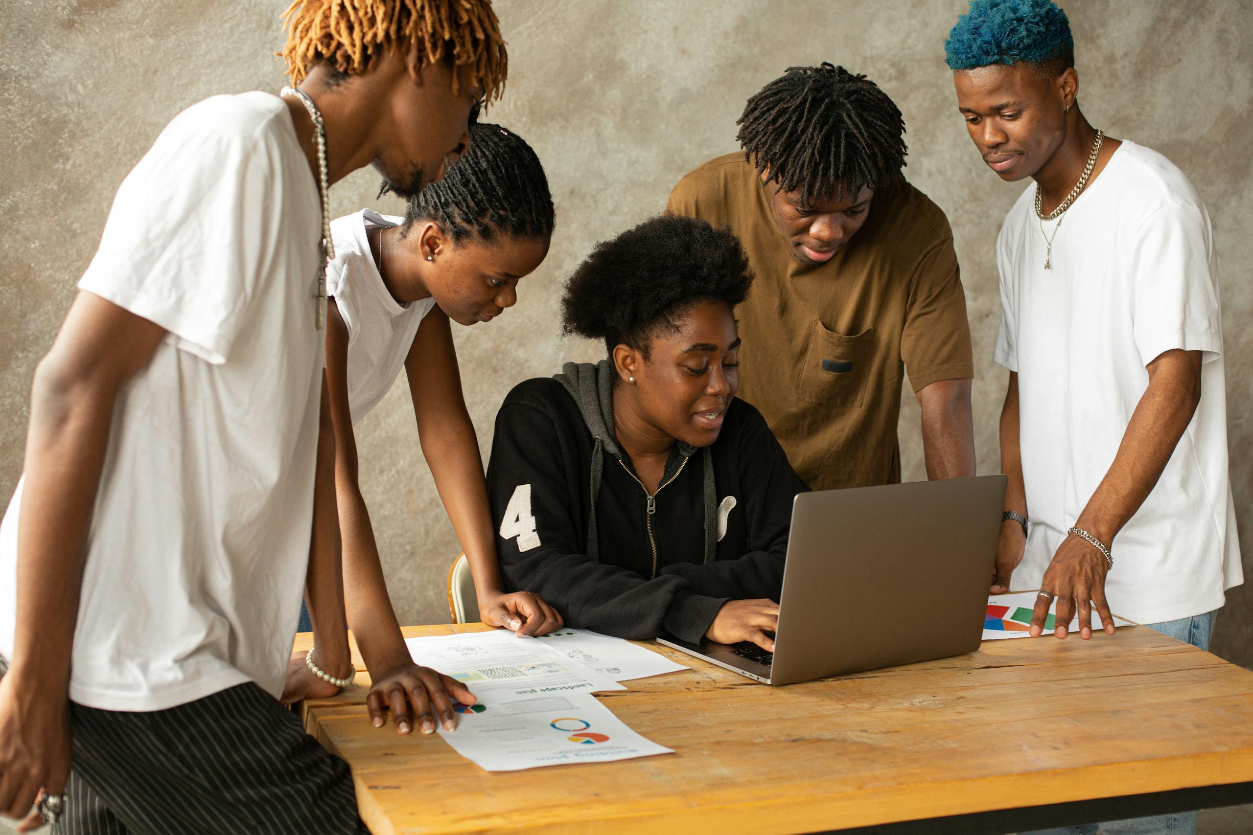 Woman surrounded by Men looking at Laptop